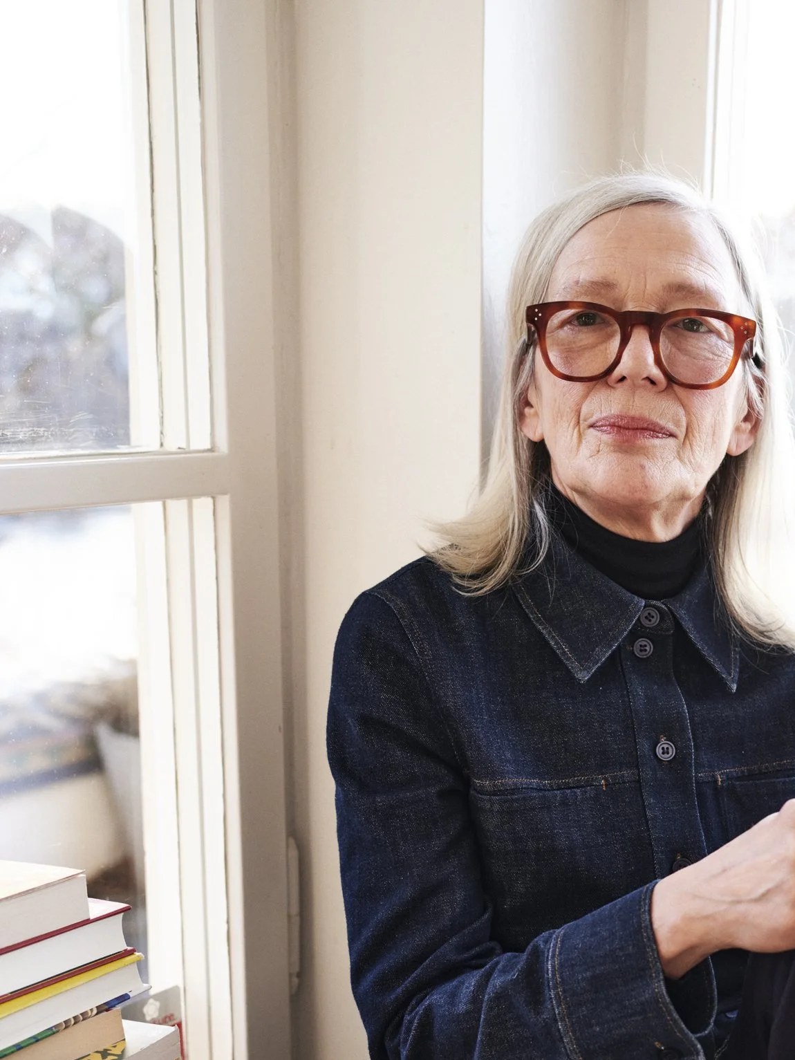 Mature woman in glasses seated beside a bright window