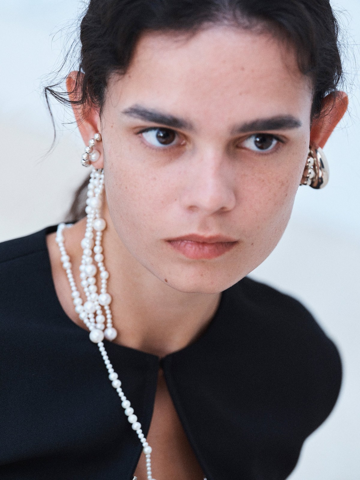 Portrait of a model wearing a black Beaufille look and pearl jewelry