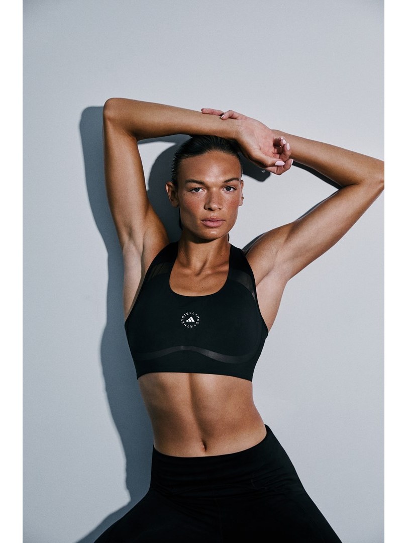 Anna Hall posing in a black sports bra and leggings with engineered mesh detail