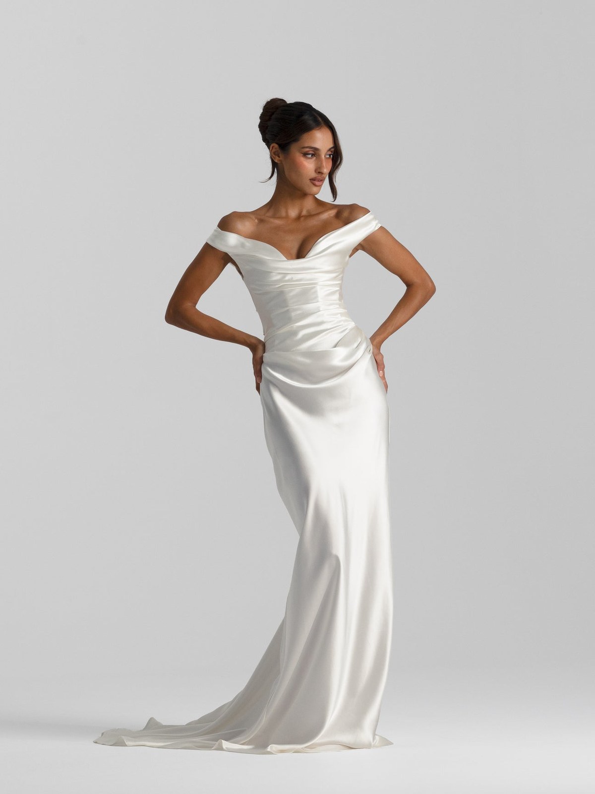 Model in a white evening gown against a soft gray studio backdrop