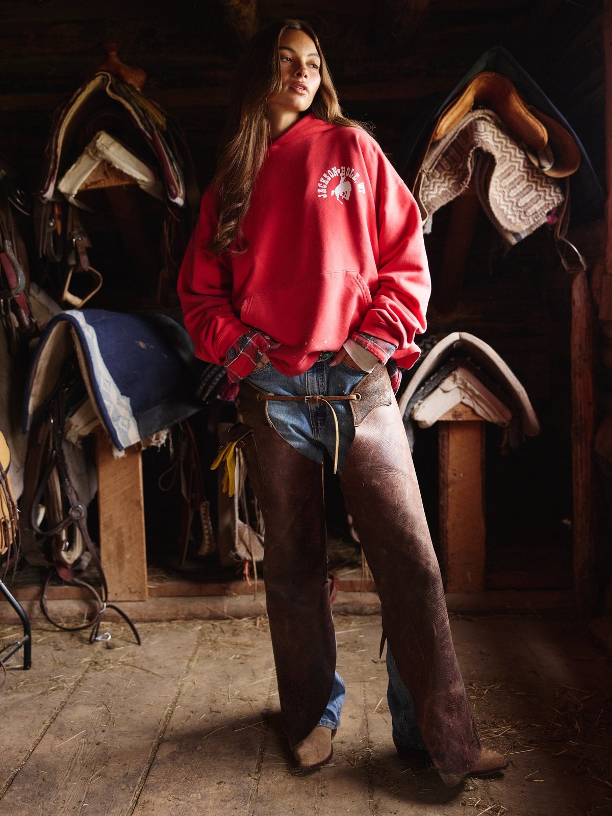 Model in a red Jackson Hole ranch hoodie in a tack room.