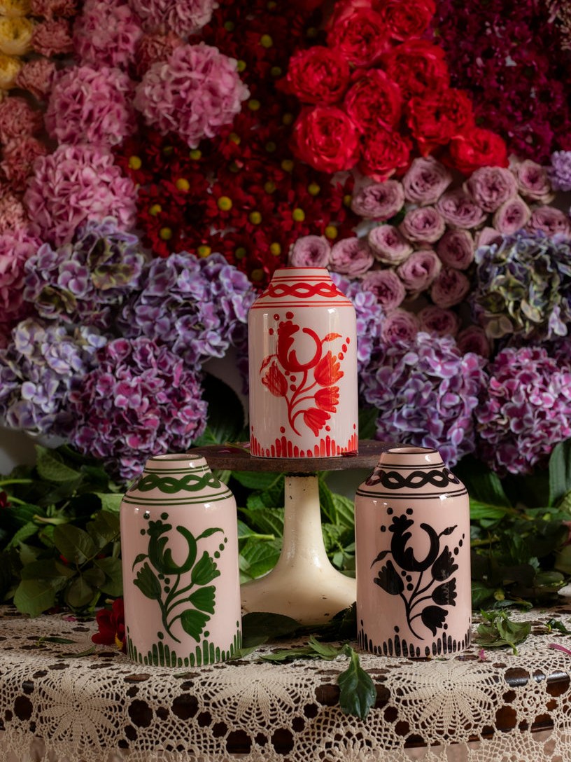 Patterned vases displayed among pink flowers on a lace-covered stand