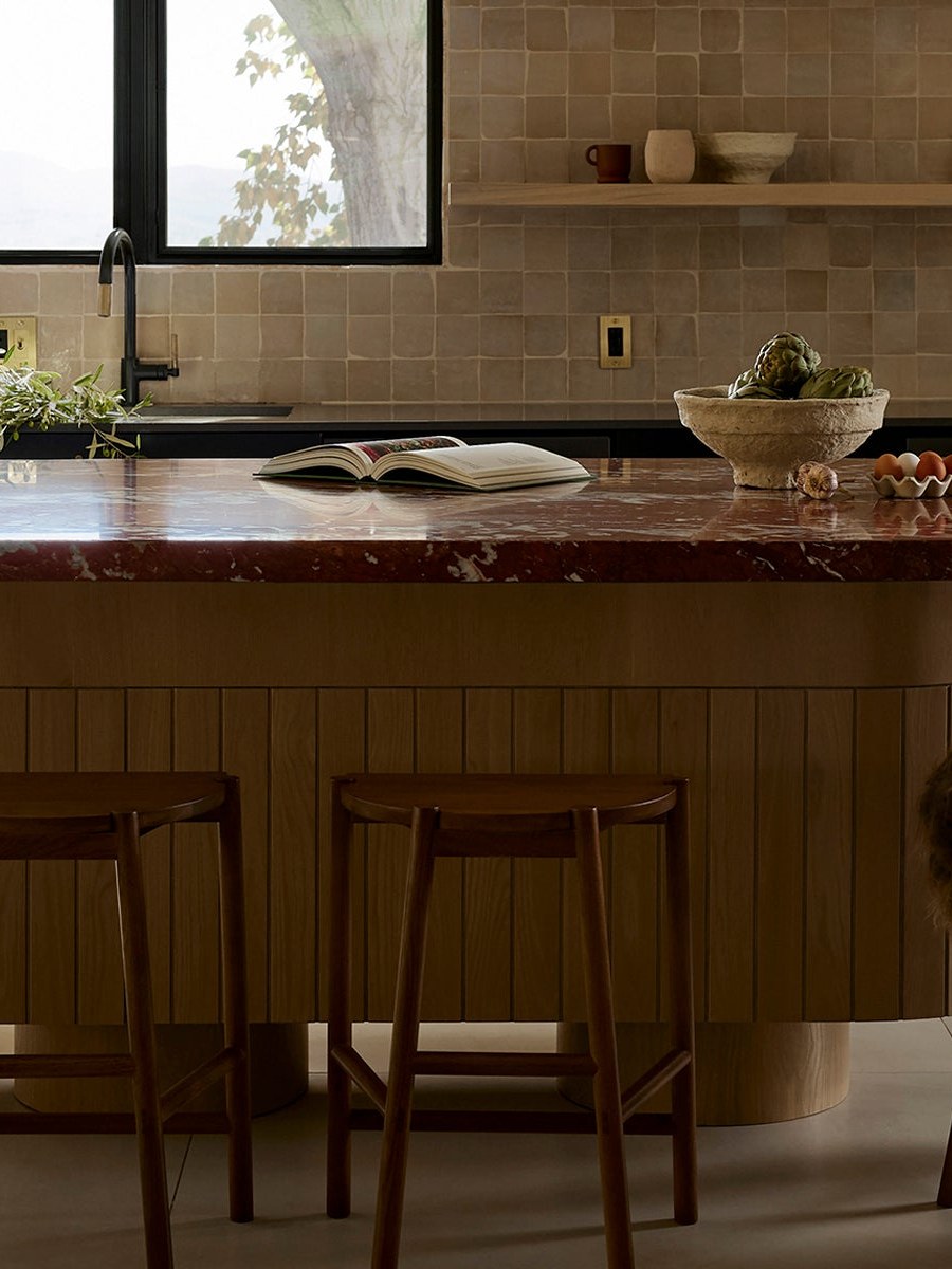 Warm modern kitchen with a dark island and simple ceramics