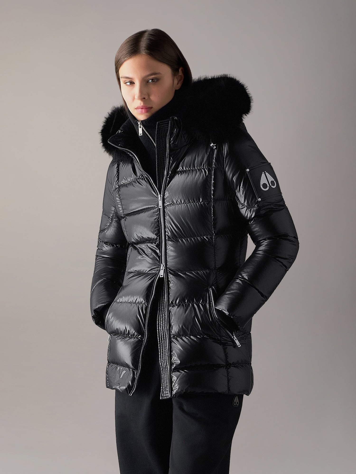 Model in a glossy black quilted puffer with a fur trim hood
