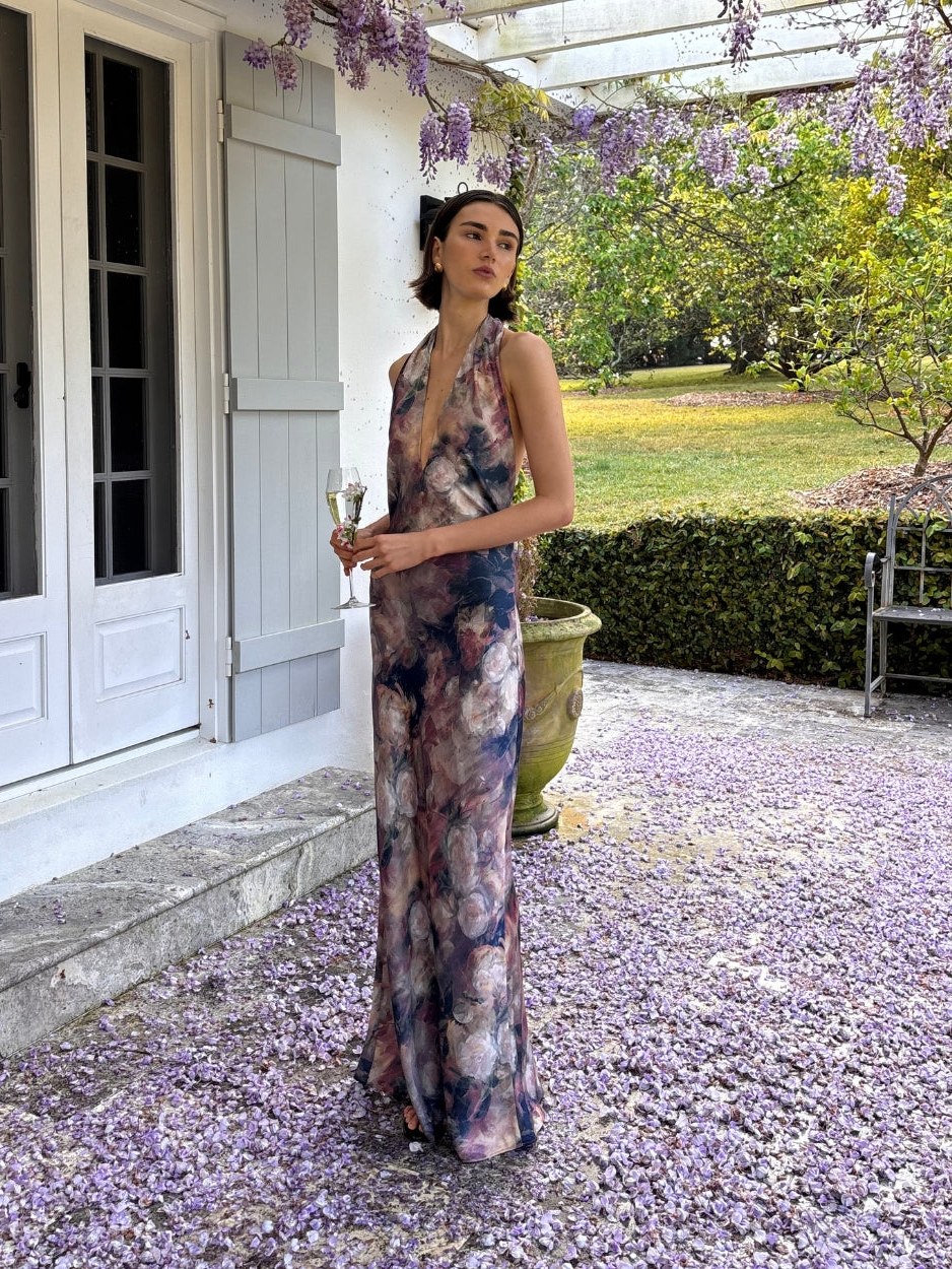 Model in a floral MINKPINK maxi dress standing in a garden courtyard
