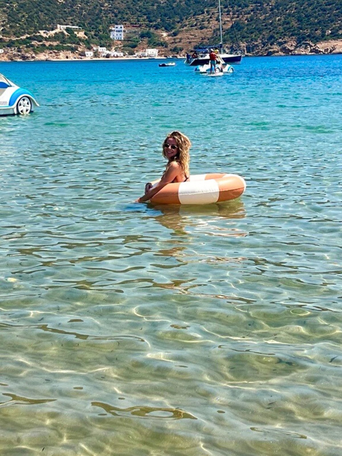 Woman enjoying an inflatable float in clear Greek water