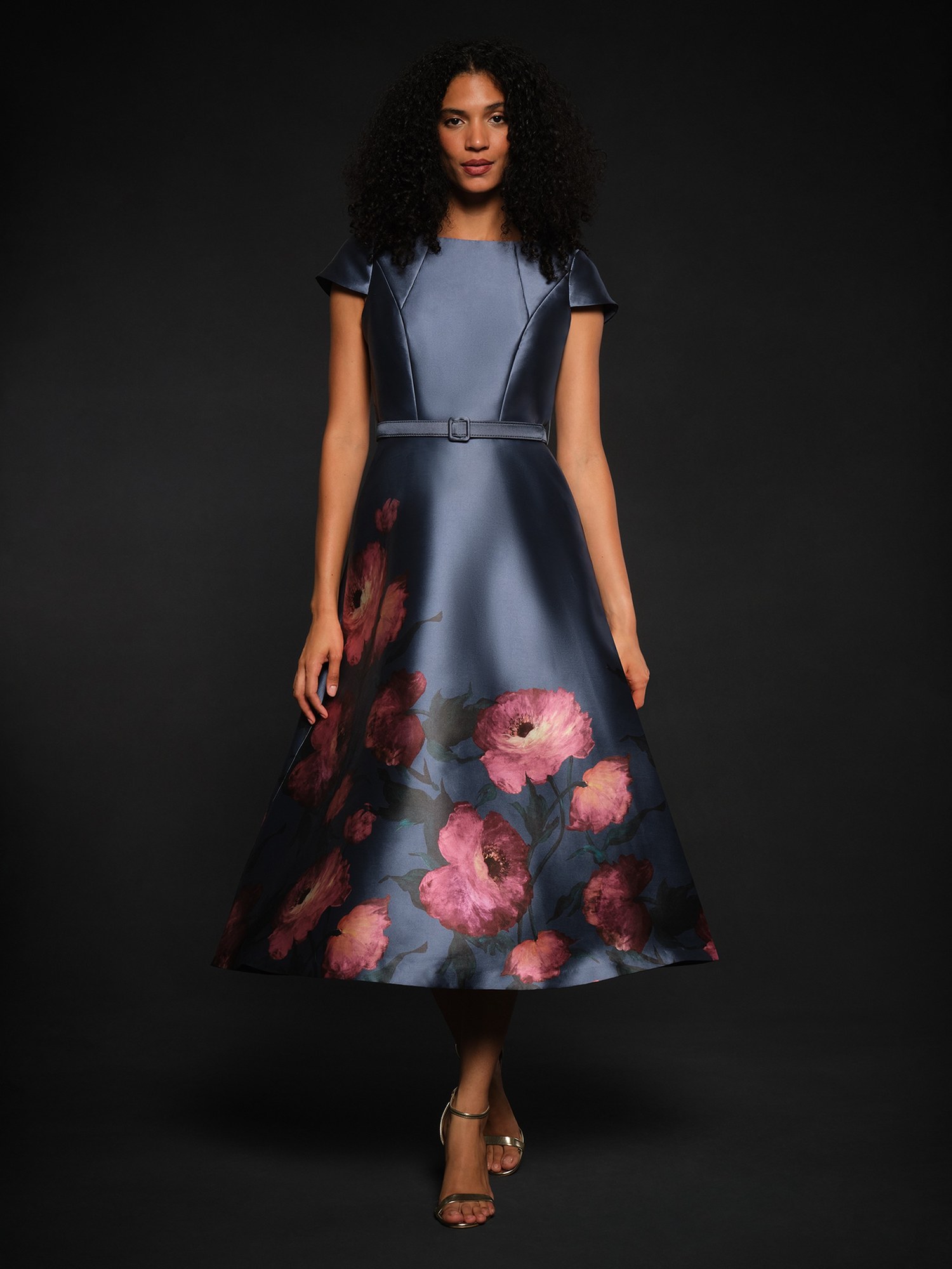 Model in a blue grey cap sleeve midi dress with a pink floral skirt
