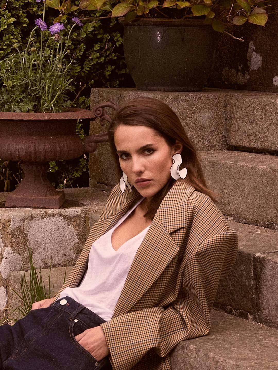Model in a checked blazer seated outdoors