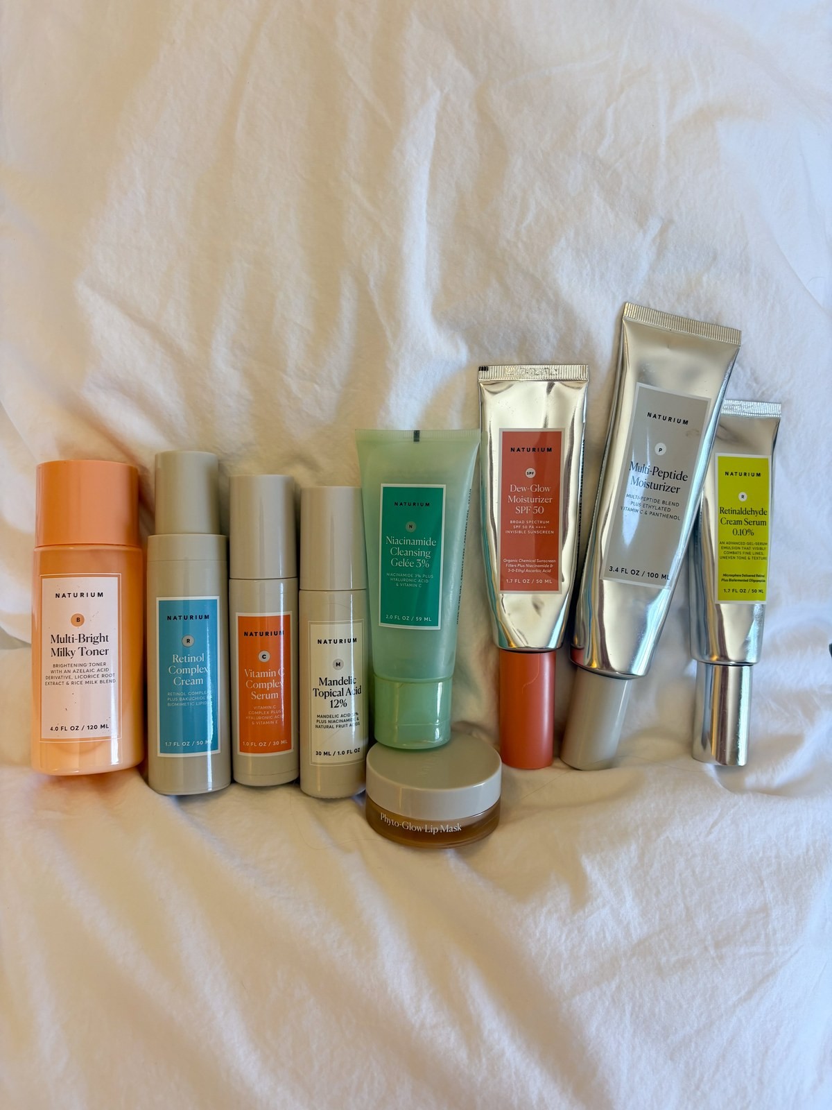 Naturium toner, serums and moisturizers lined up on a white sheet