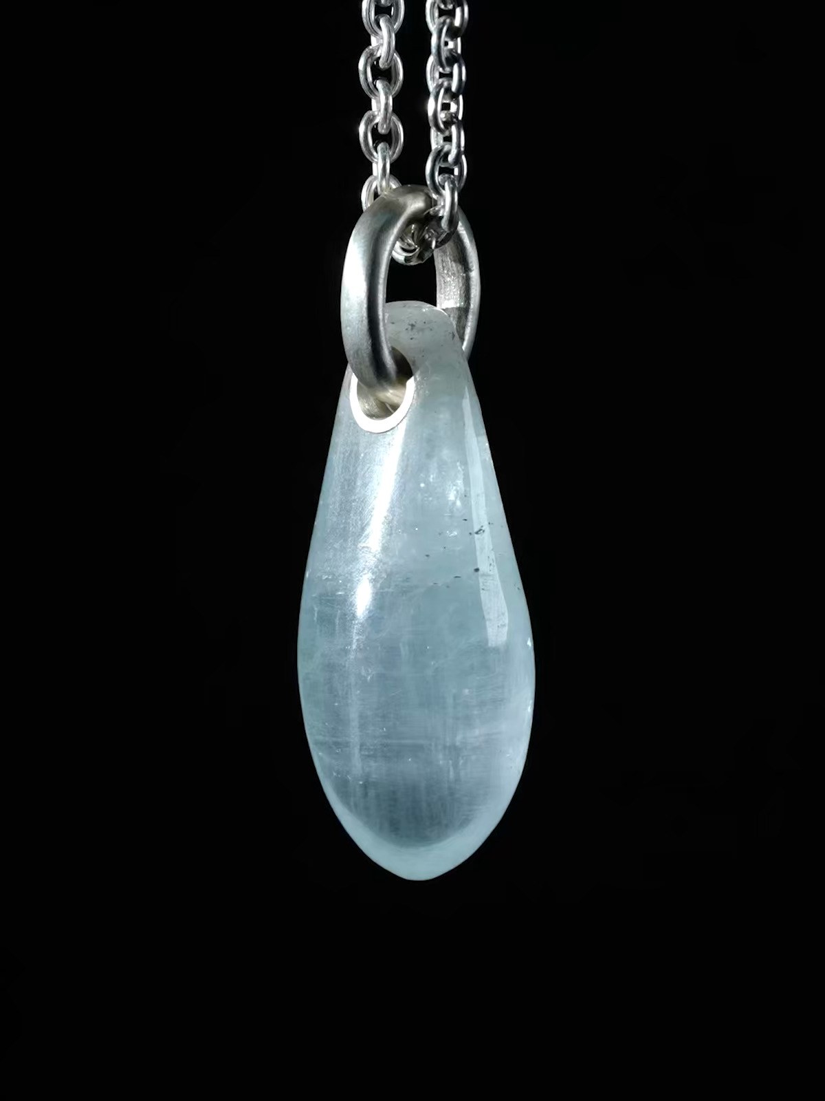 Aquamarine pendant hanging against a black background