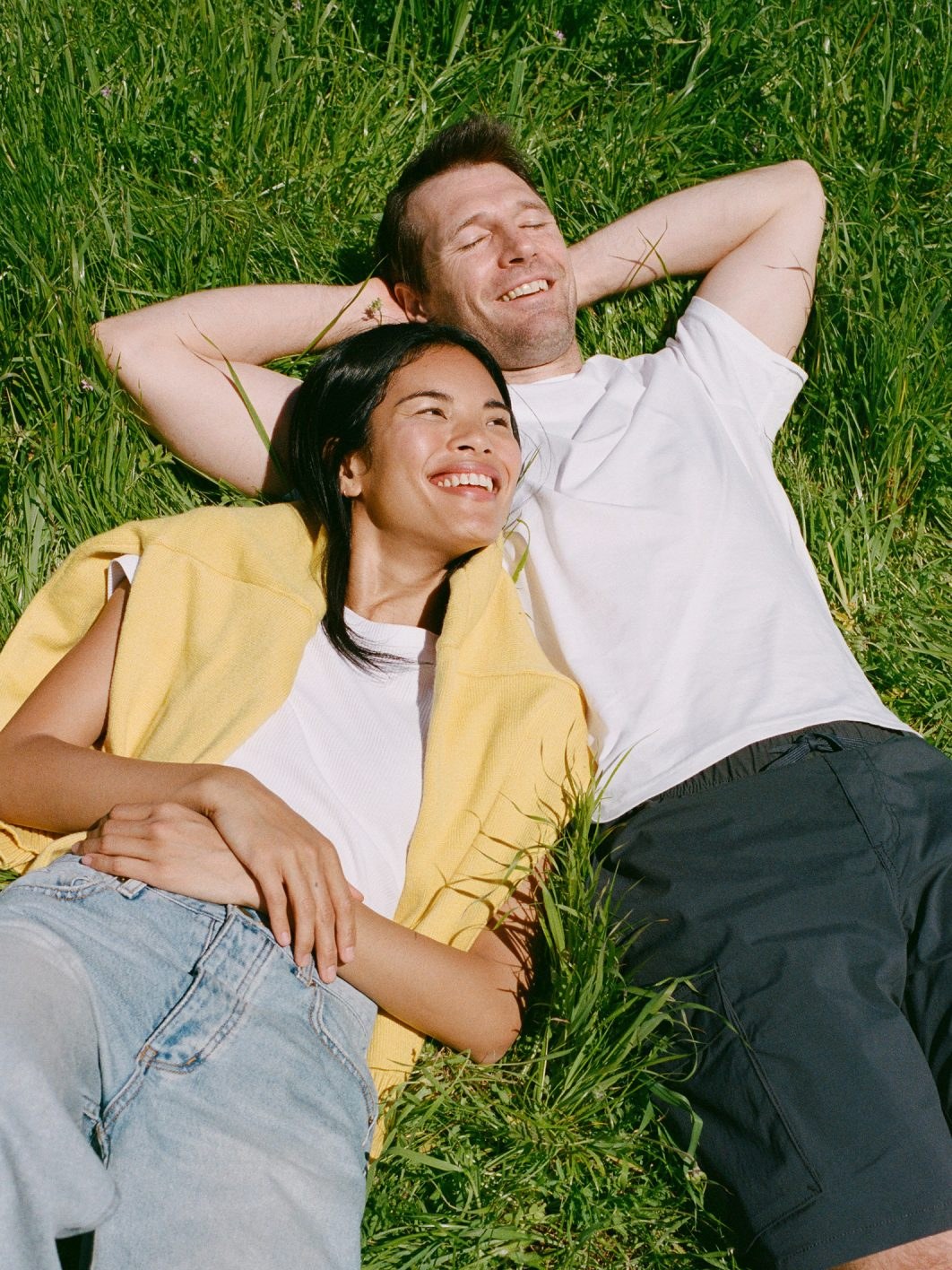 Two smiling people resting in the grass in bright sun during an Ursa Major campaign