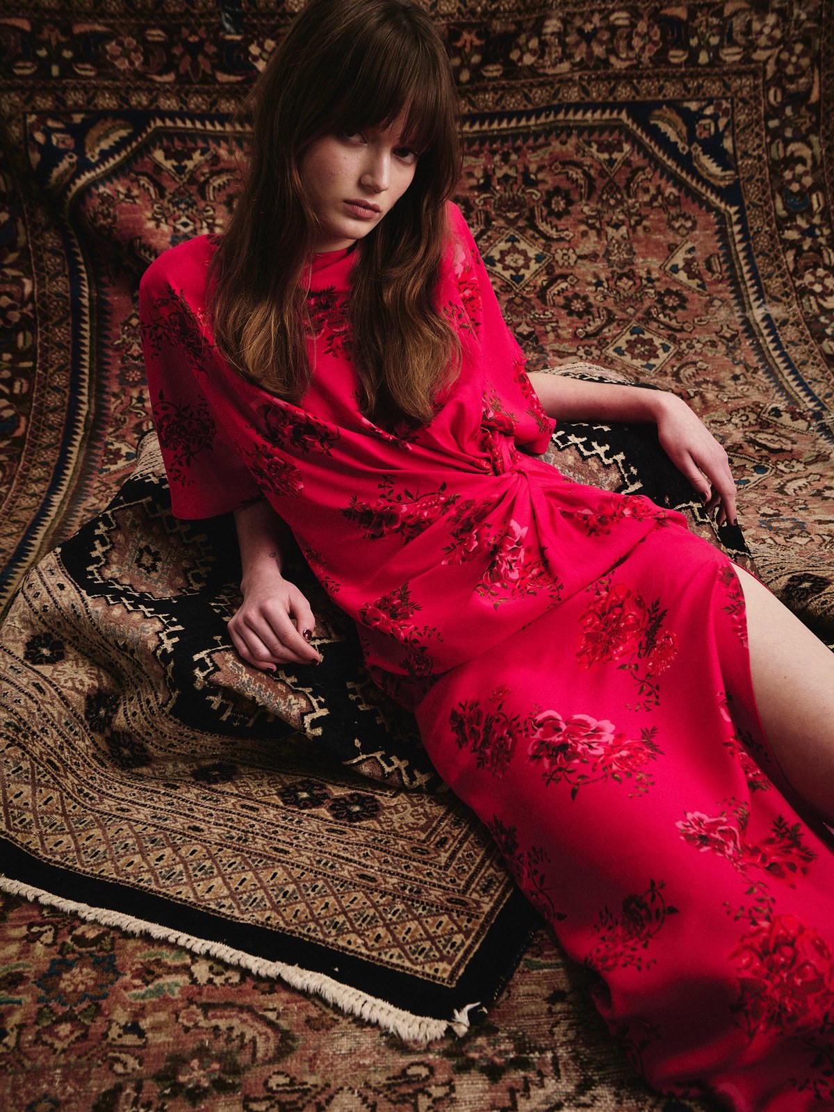 Model in a red printed dress reclining on a patterned rug