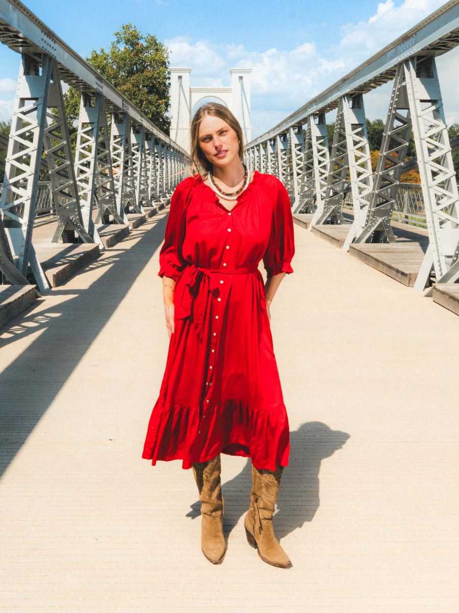 Woman in a red button-front dress on a steel pedestrian bridge