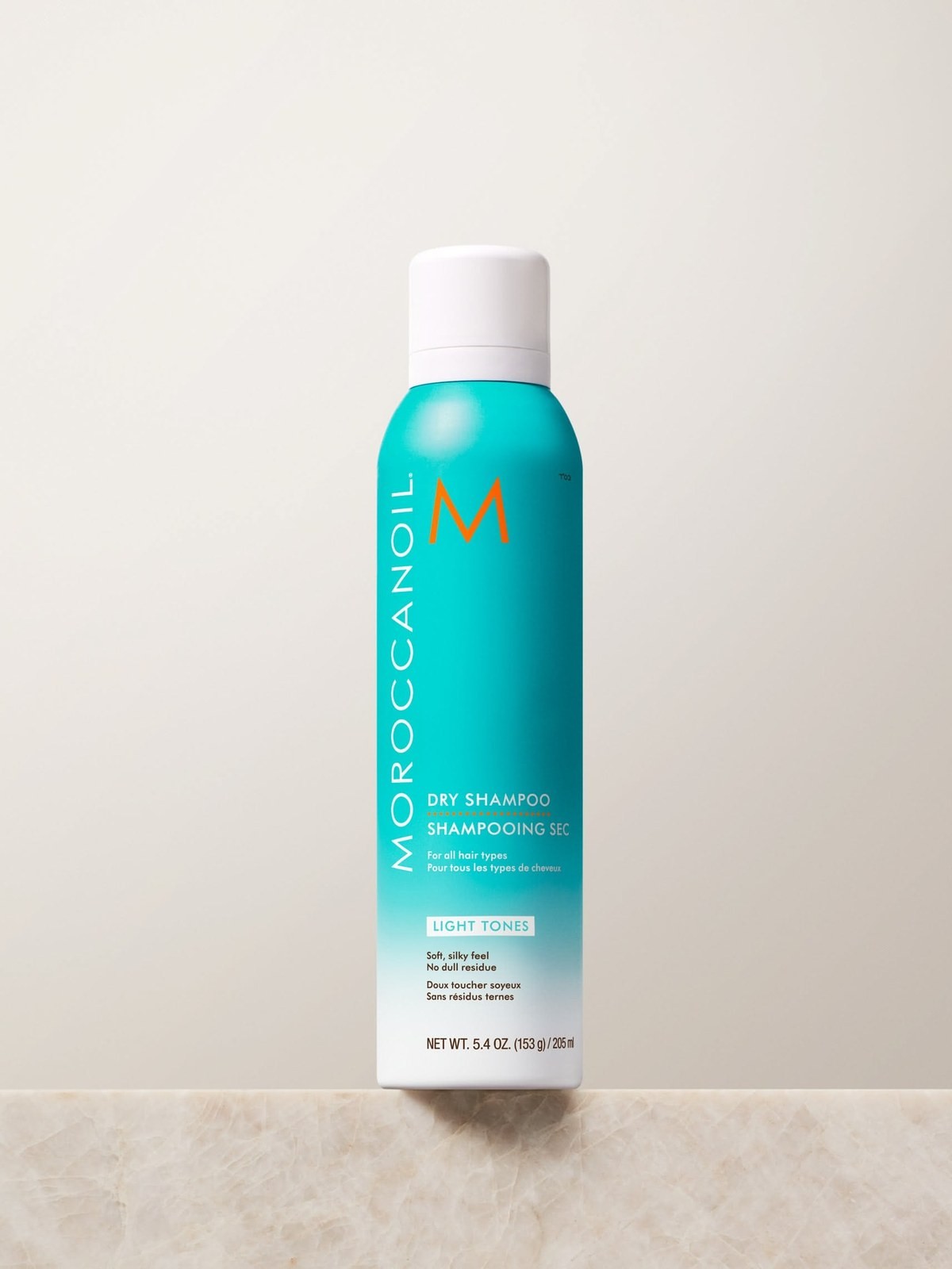 Teal Moroccanoil Dry Shampoo Light Tones can on a marble ledge