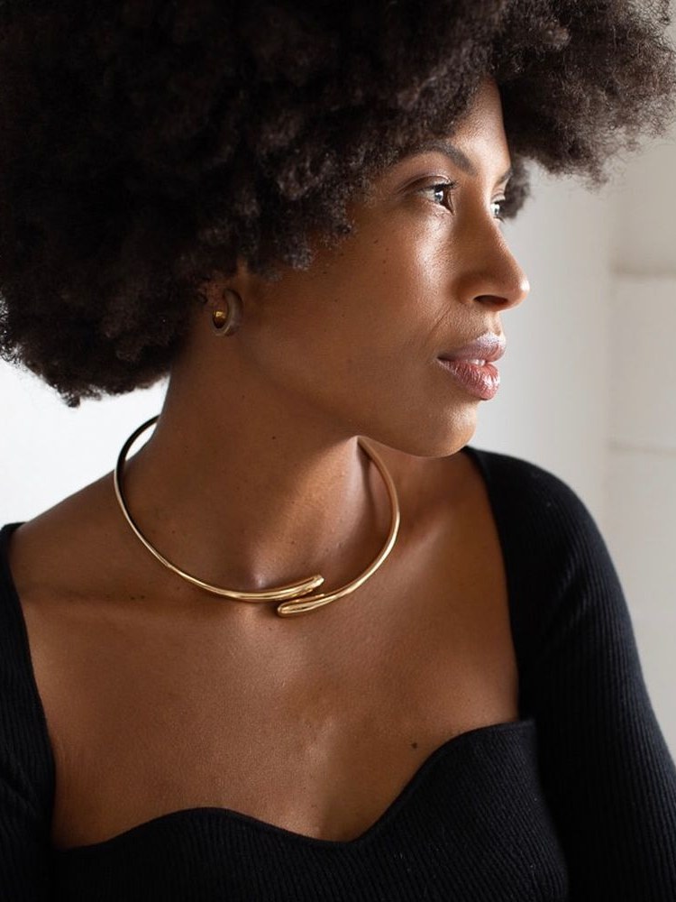 Model with natural hair wearing a sculptural gold choker