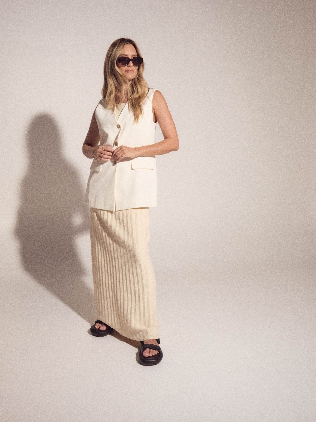 Full-length model in a white tailored outfit and Luv Lou sunglasses in a studio