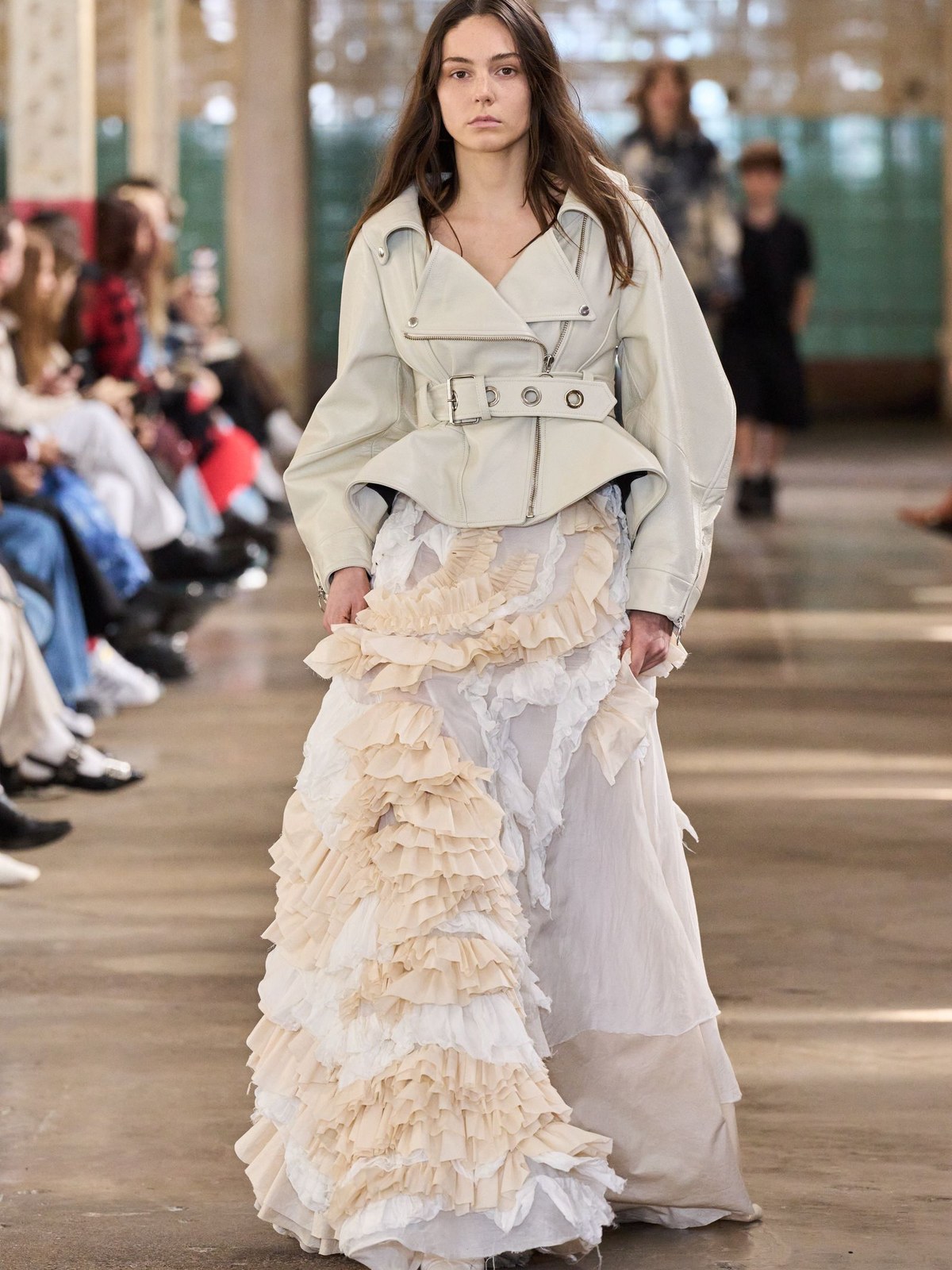 Runway model in a tiered white gown with soft, irregular layers