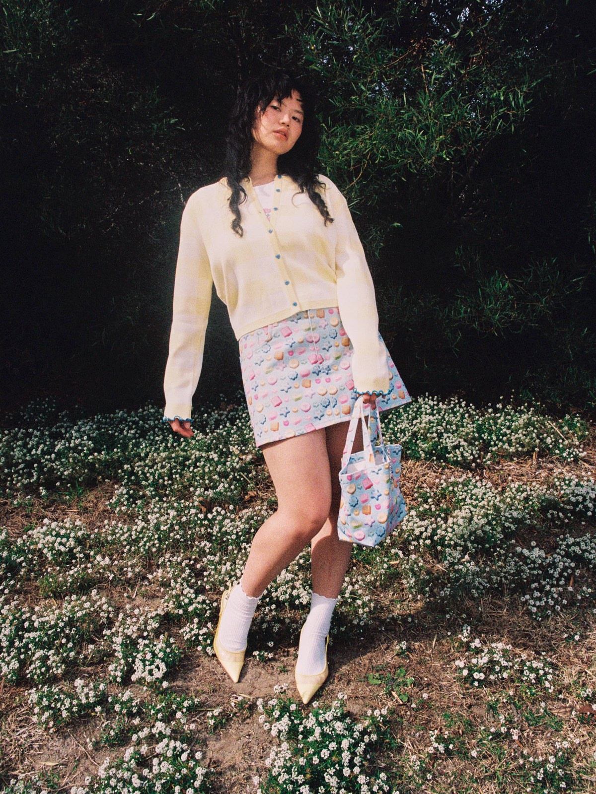 Woman in a candy-colored Lisa Says Gah print skirt outdoors among flowers