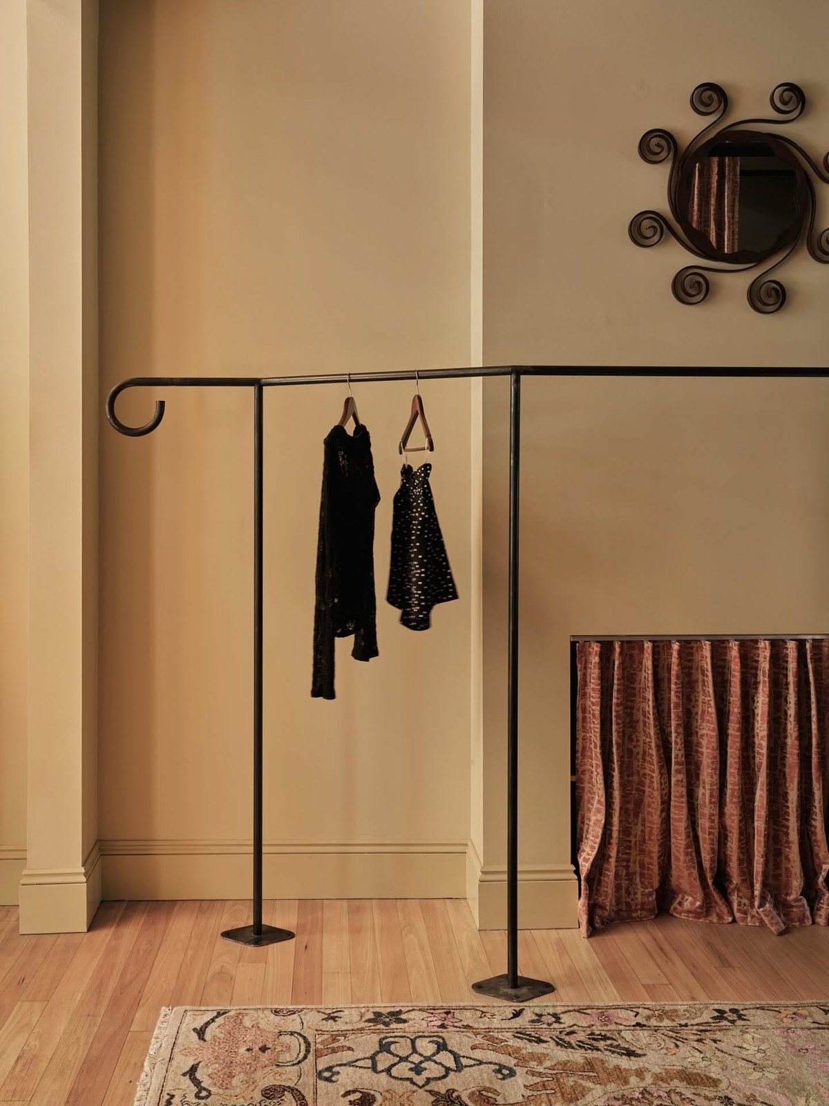 Two pieces hanging on a sculptural rail in a warm, sparse room