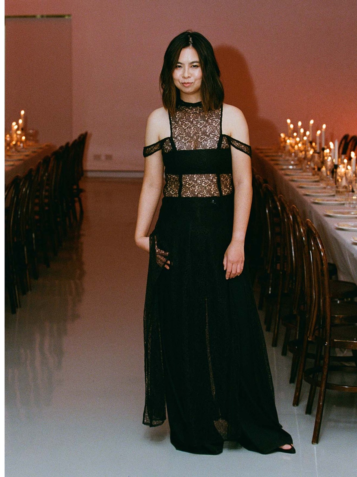 Model in a black evening dress at a candlelit runway dinner