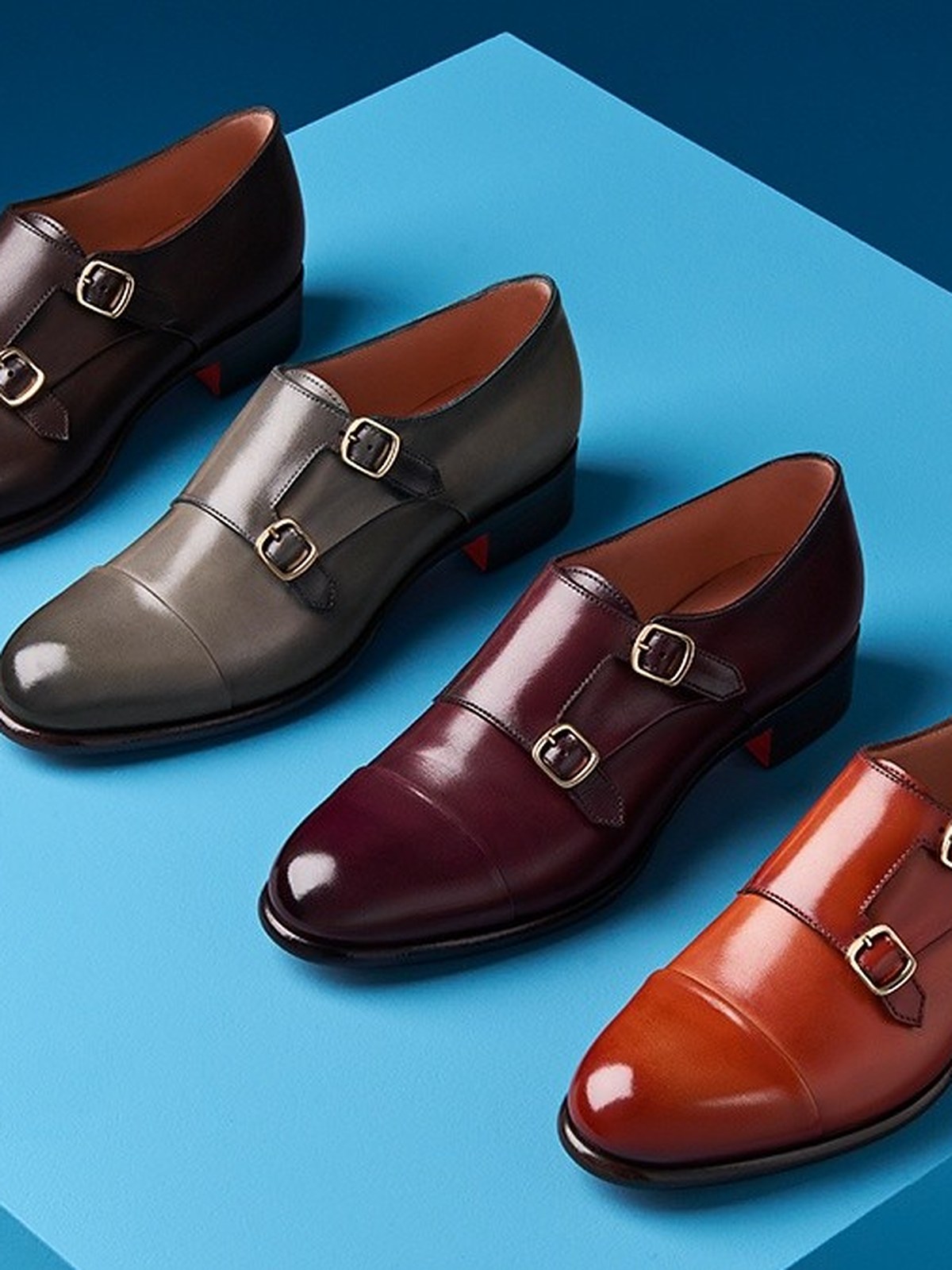 Four double buckle monk strap shoes on a light blue plinth
