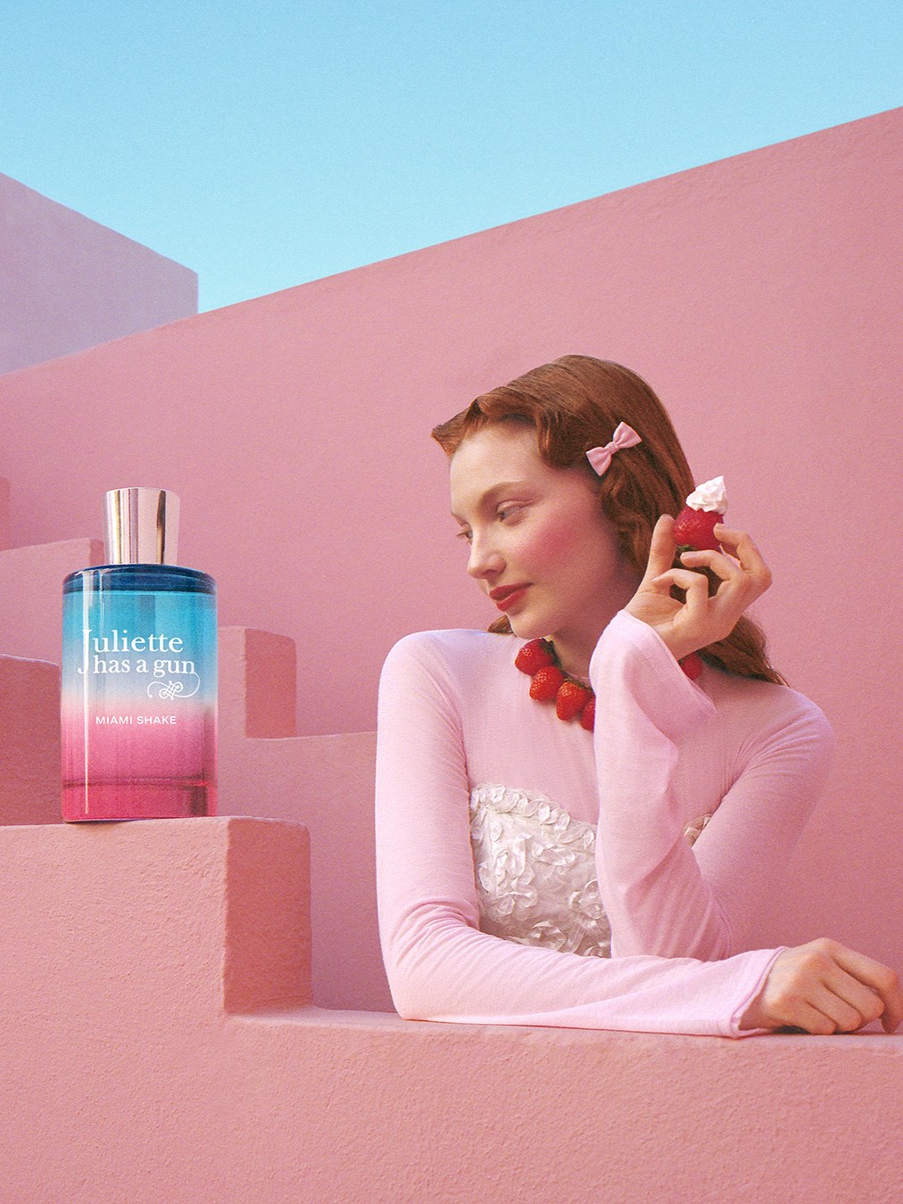 Woman in a pale pink look seated among sculptural pink steps with Miami Shake