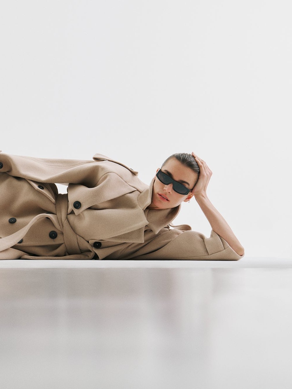 Model reclining in a camel coat from the Fall Winter lookbook