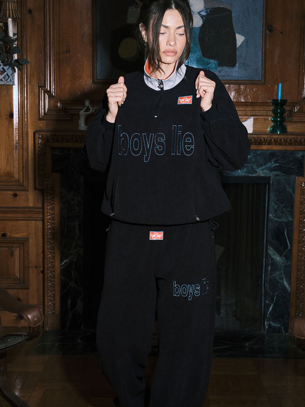Model in a dark graphic tracksuit in a wood-paneled room