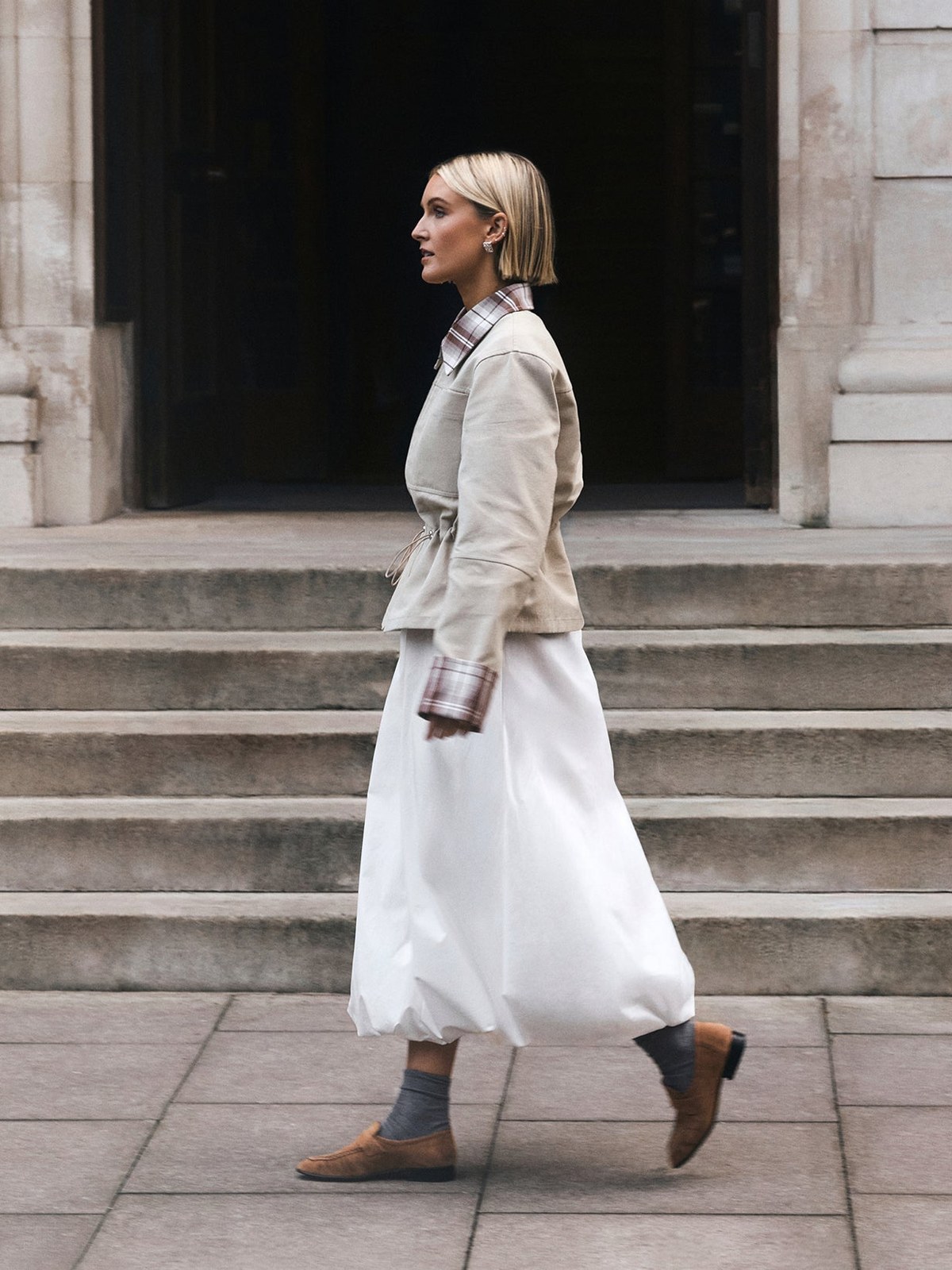 Model walking in a pale jacket and white skirt for ALIGNE’s SS26 campaign
