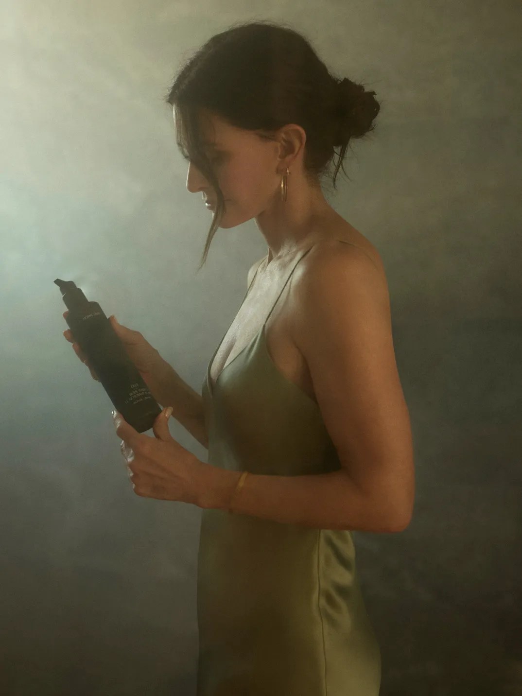 Courteney Cox holding a Homecourt bottle in a softly lit studio