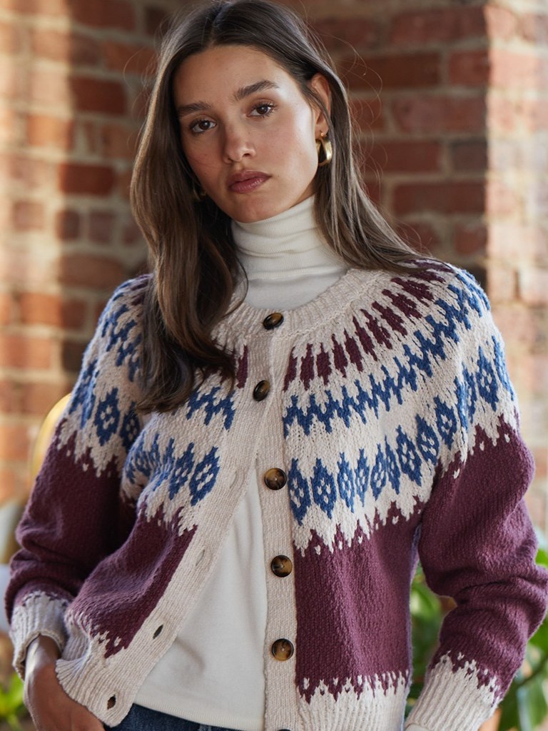 Model in a patterned cardigan inside a brick-lined room