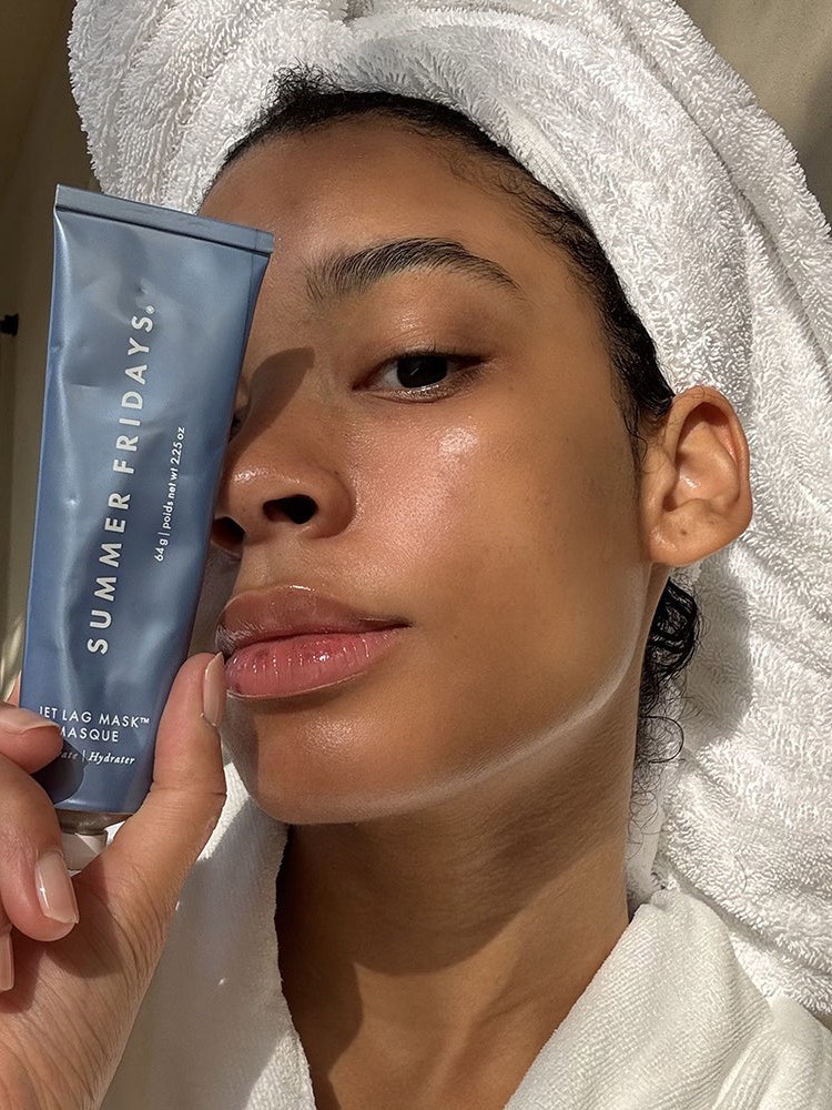 Woman with a towel wrapped around her hair holds a Summer Fridays product