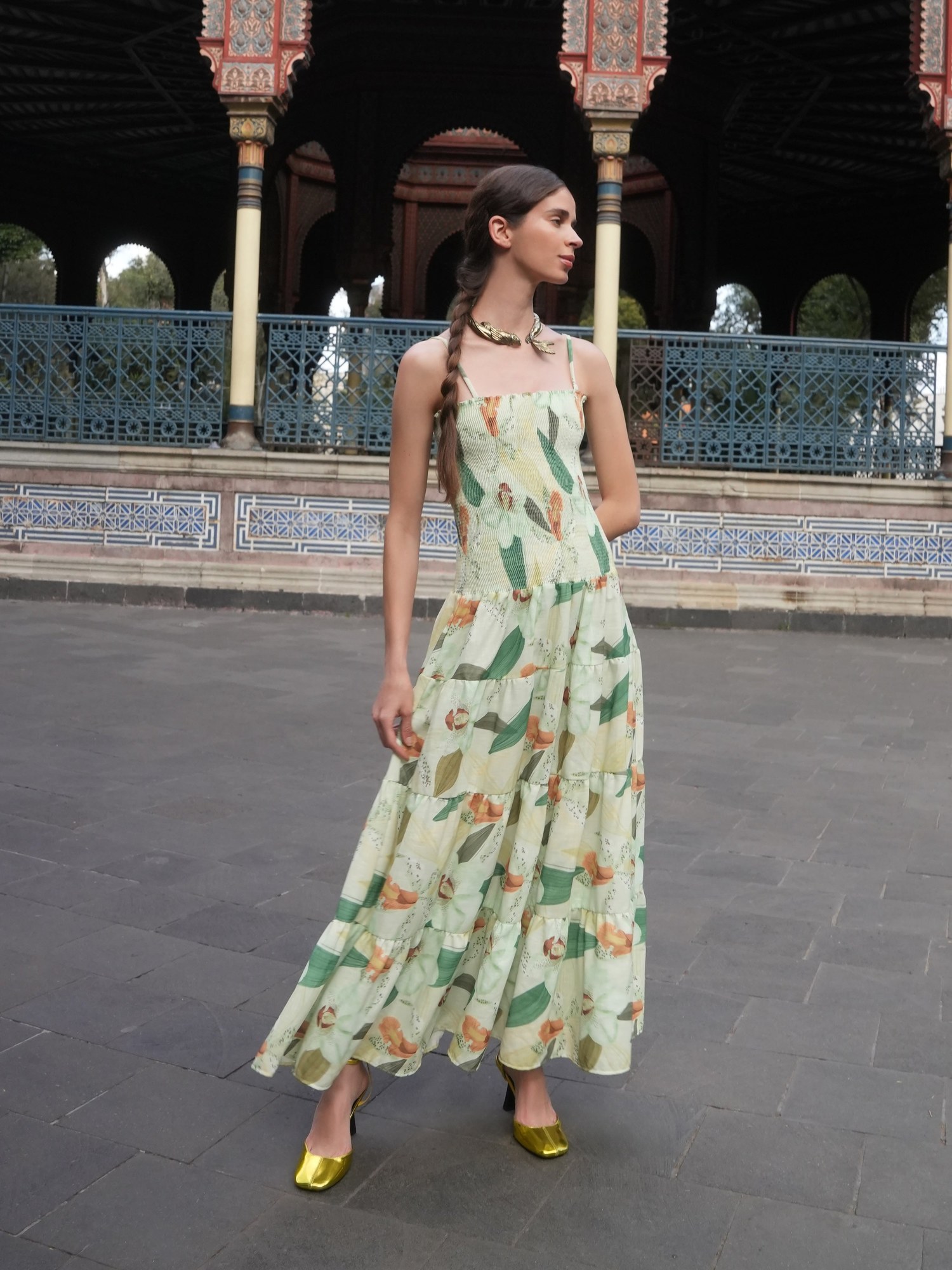 Model in a green and yellow printed tiered maxi dress under a Moorish pavilion