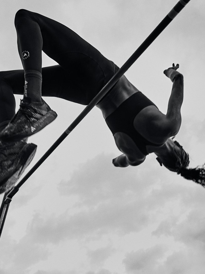 Anna Hall vaulting with a pole in black training gear against an open sky