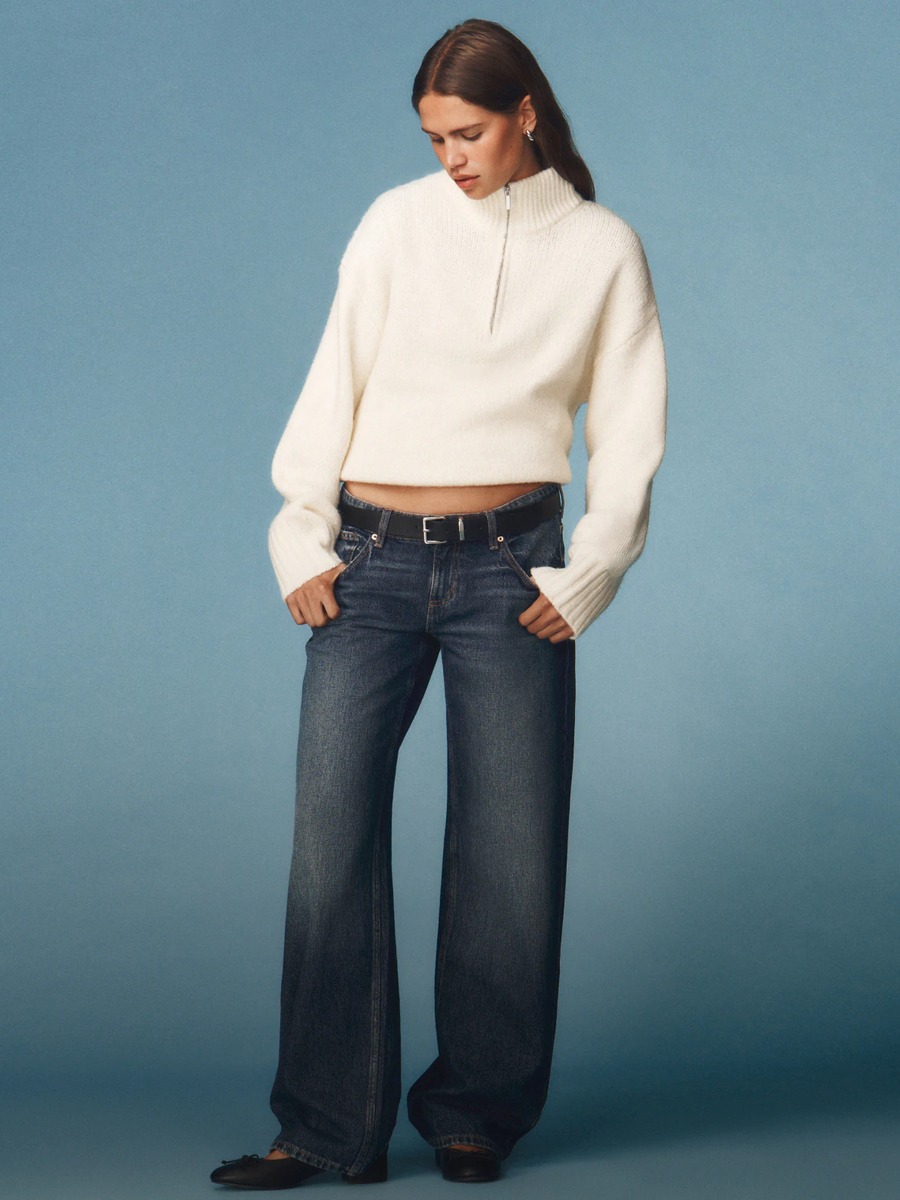 Cotton On campaign photo of a woman in a cream half zip sweater and dark wide leg jeans