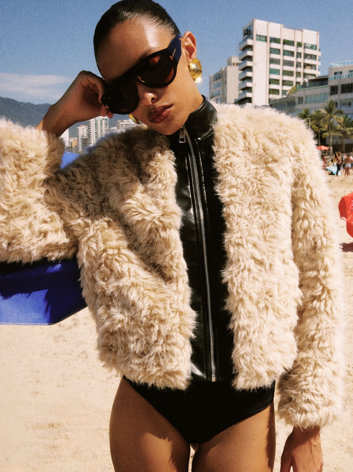 Model in a textured beige faux-fur jacket at a beachside street