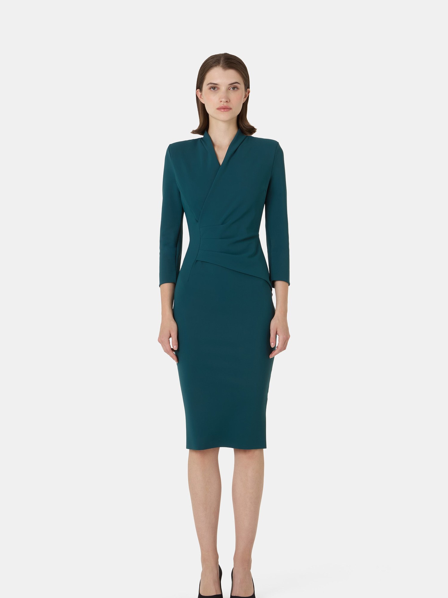 Model in a teal wrap effect long sleeve sheath dress with black pumps