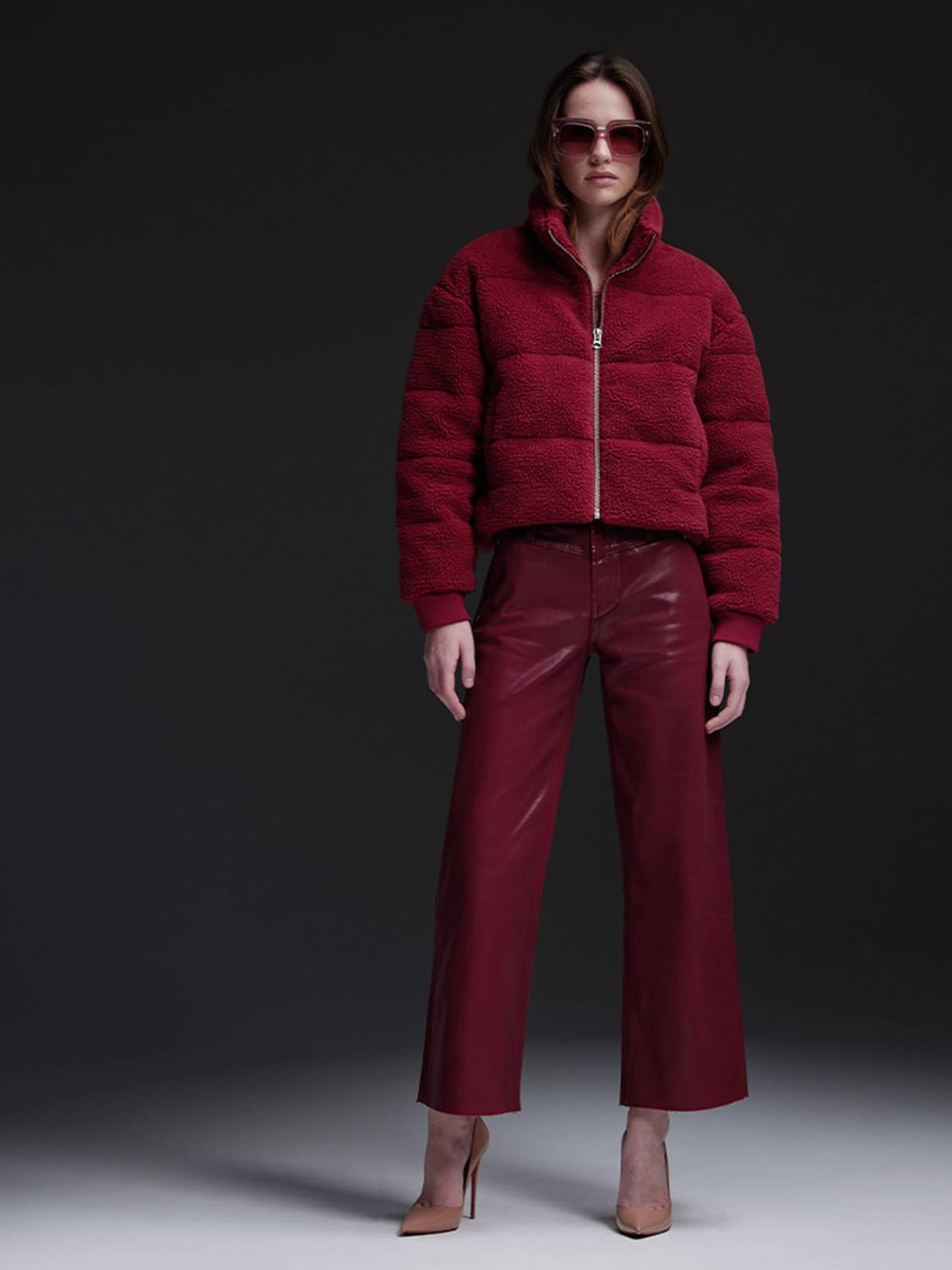 Model in a red jacket and matching trousers against a dark studio backdrop