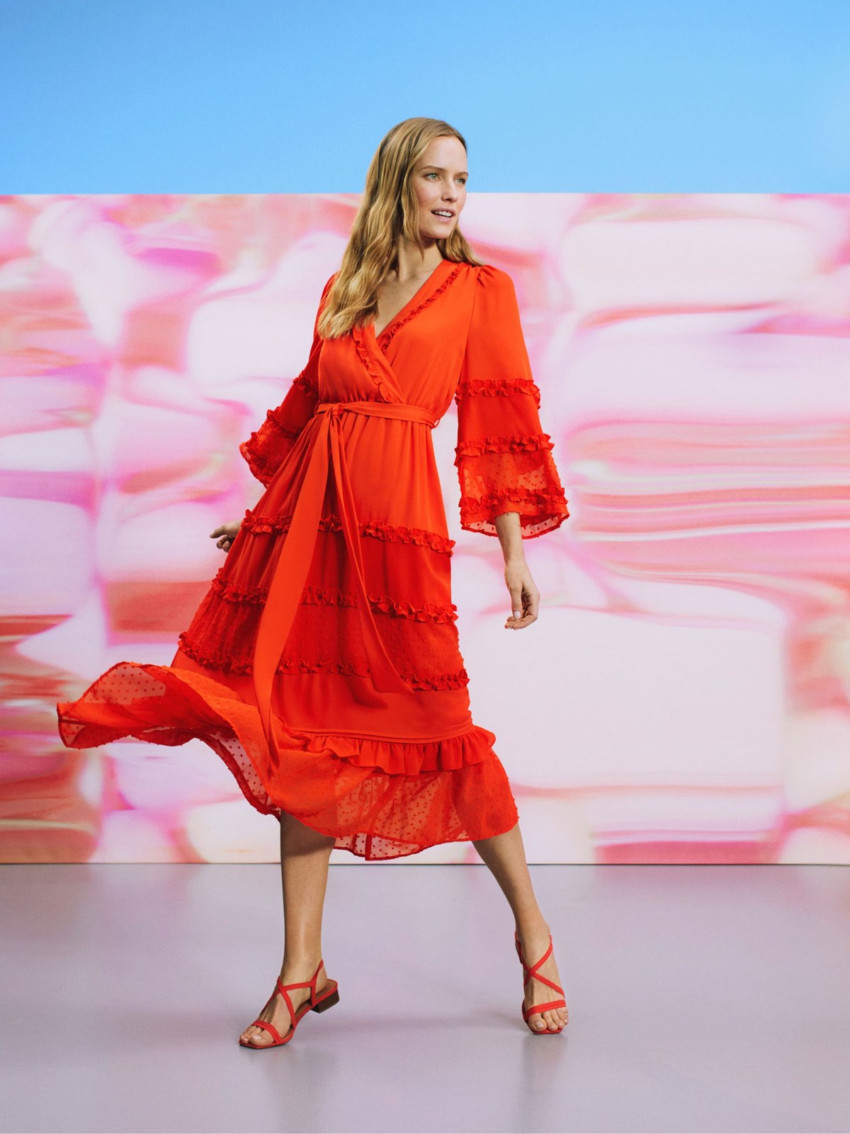 Model in a red tiered ALEXIS for Target dress against a vivid pink set
