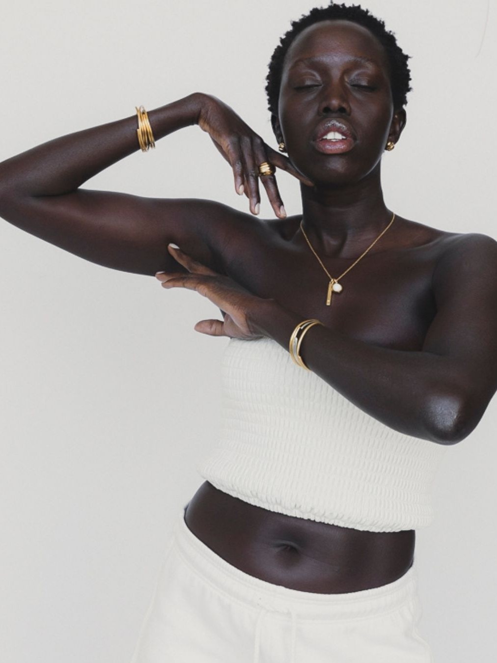 Model in a white top wearing layered SOKO necklaces and gold jewelry