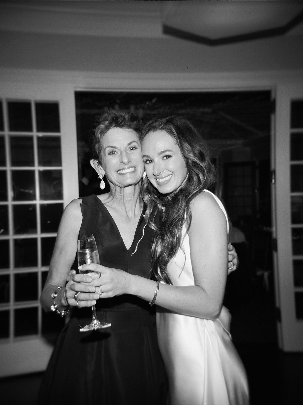 Brinker and Eliza Higgins smiling together in dresses and jewelry