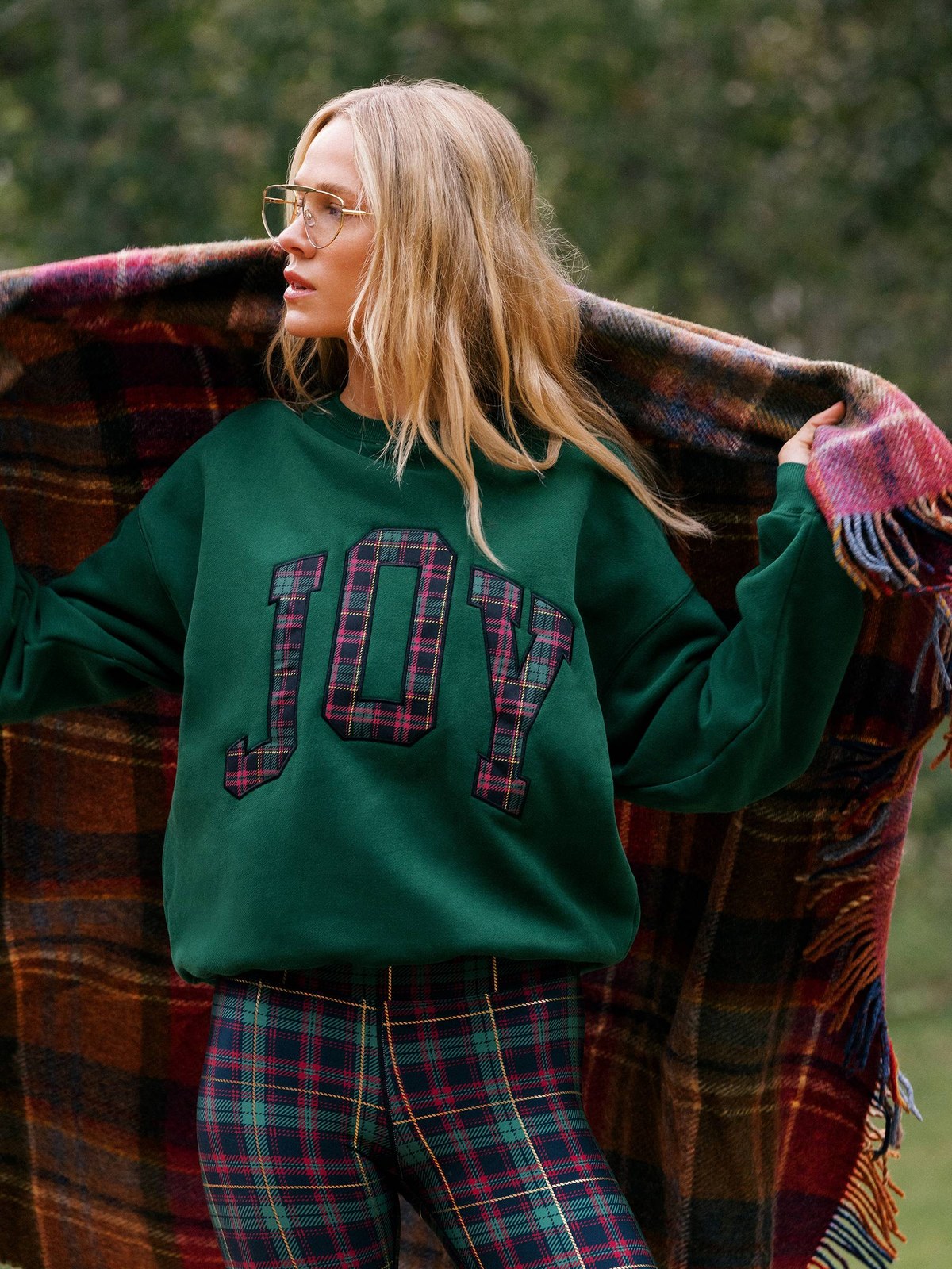Woman in a green sweatshirt and plaid trousers outdoors