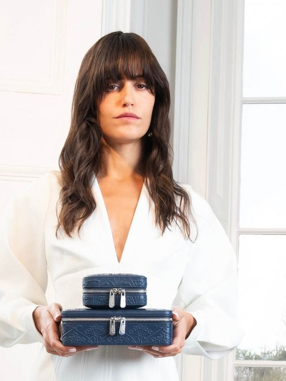 Woman in a white blouse holding a navy WOLF jewelry case