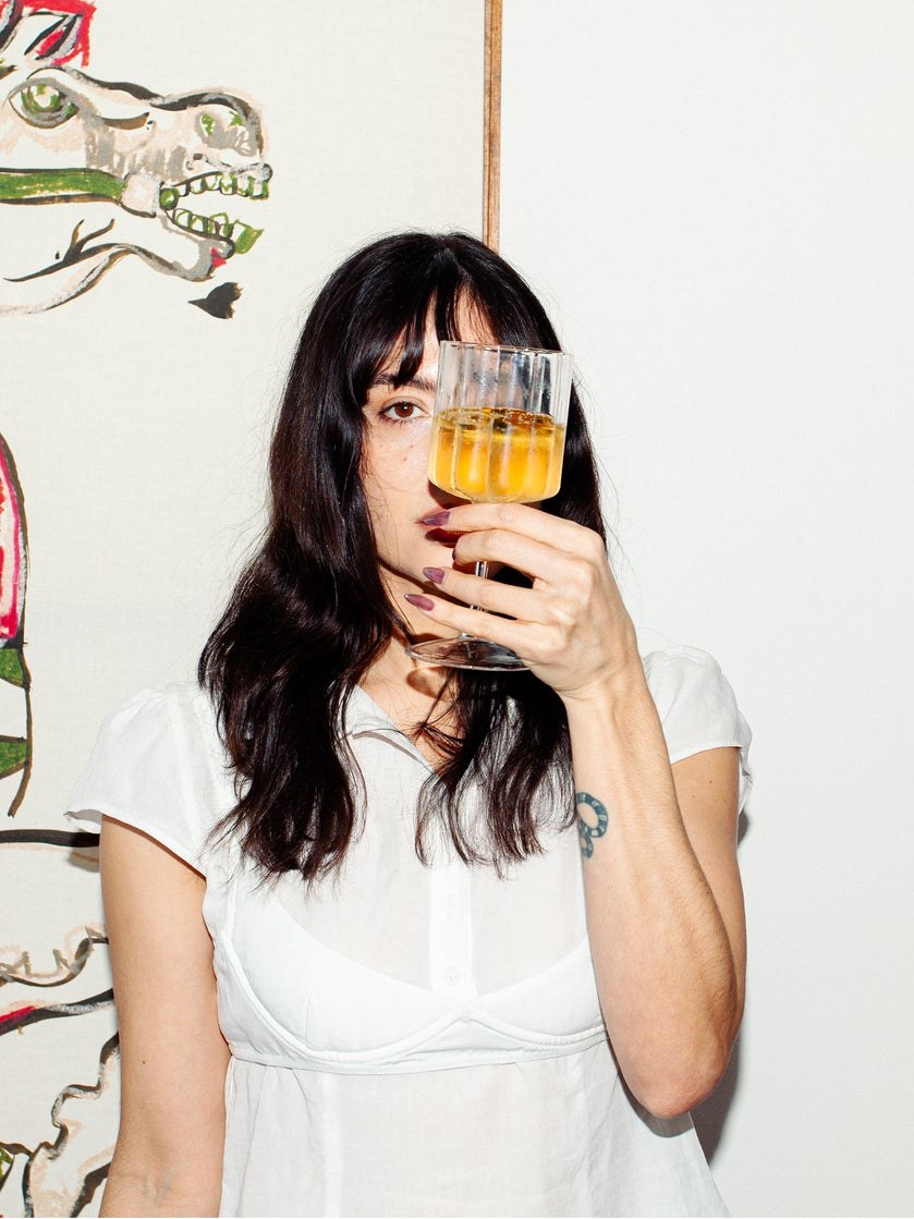 Brooke Holiday holding an amber drink in her art studio