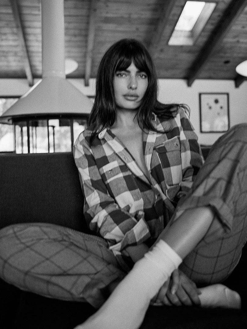 Woman in a plaid outfit seated indoors in a black and white campaign photo