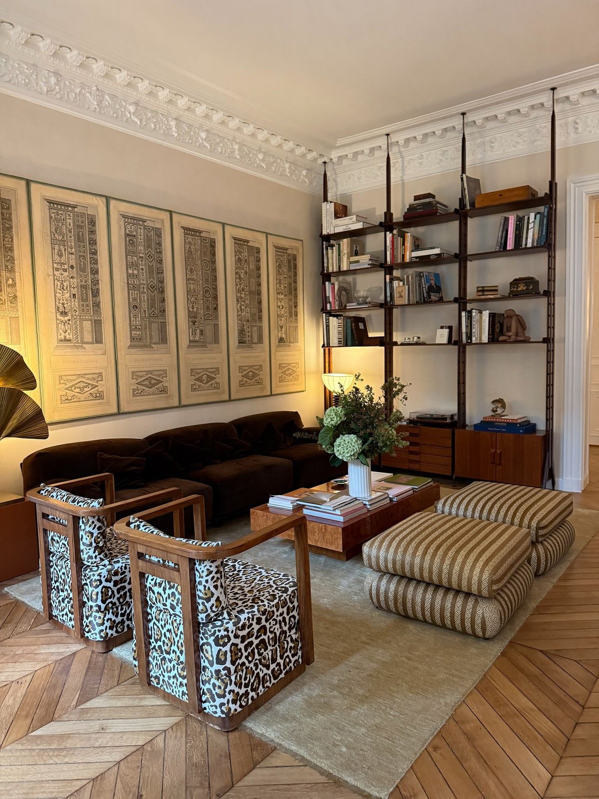 Living room with framed prints, patterned armchairs and open shelving
