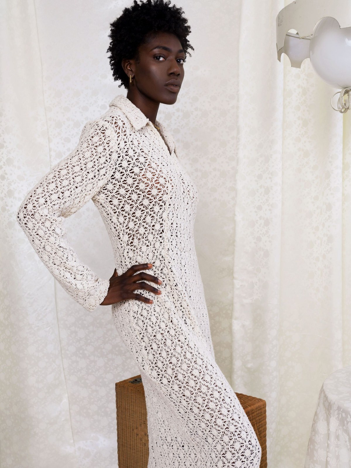 Model in a cream crochet dress in a styled interior