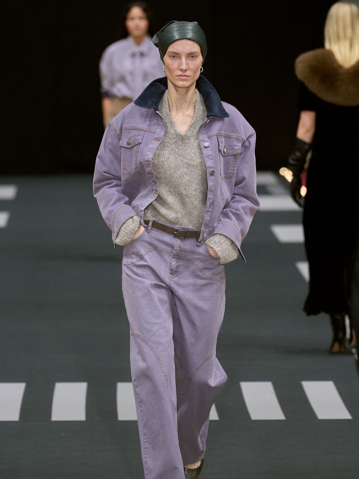 Runway model in a pale lilac jacket and matching trousers with a dark beret