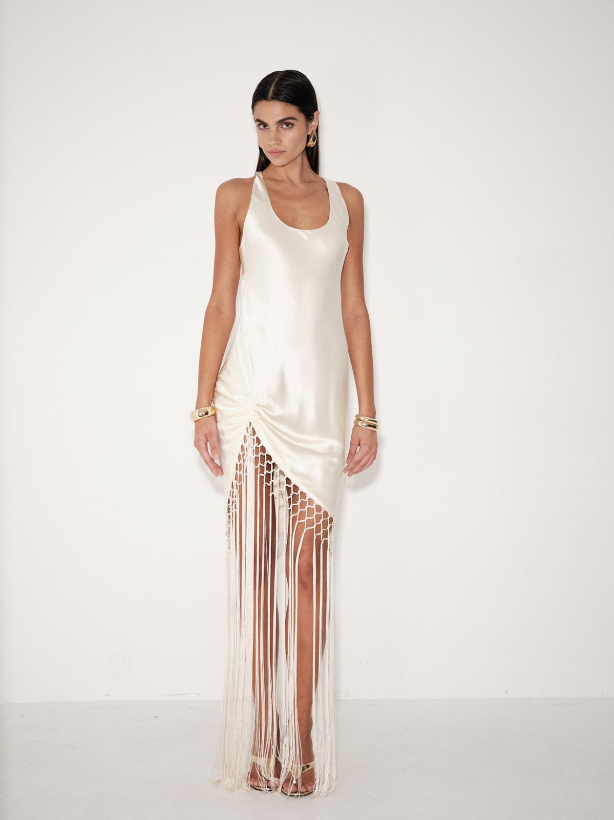 Model in a white Delfi dress with long fringe in a pale studio