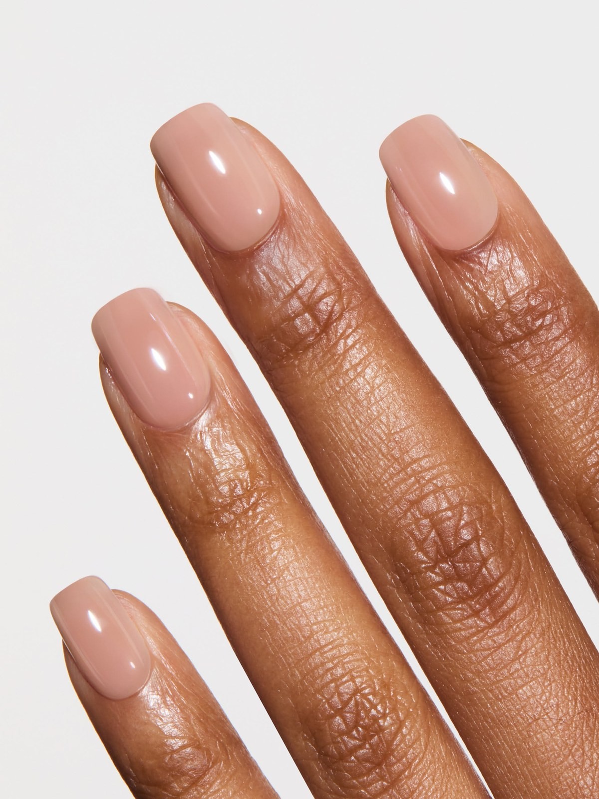 Close up of a hand with glossy nude square-shaped gel nails
